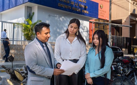 Legal consultation outside the Piura District Office, Piura, Peru. People discussing documents.